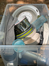 RV rental ready: essential camping kitchenware in a clear bin, including pots, plates, cups & towels for easy travel.