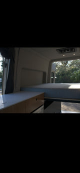 Inside this rv rental: comfy bed, sleek counter, and bright nature view. Ideal for road trips and camping.