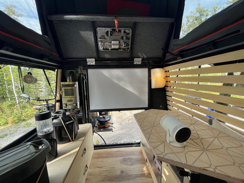 Experience outdoor living with this RV rental's clever interior: a bed, projector setup, and a compact kitchen. — photo 18