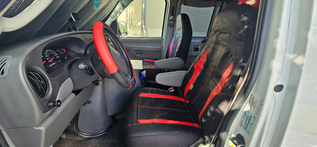Inside an RV rental van: driver's seat with red/black covers, dashboard, and steering wheel visible.
