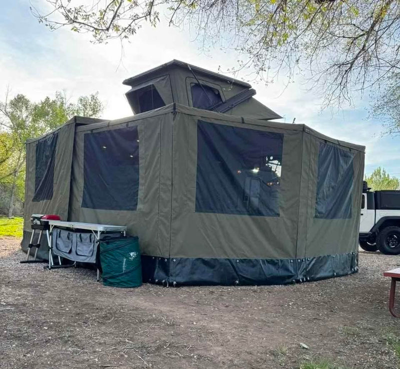Bush Company 270 XT MAX wall kits fully zipped in around the XPedition Voyager Sky XE at camp, creating a large enclosed screened outdoor room with the rooftop tent open above — photo 16