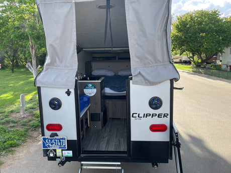 Explore the interior of this Clipper pop-up rv rental, featuring a bed, kitchen area, and Montana license plate.
