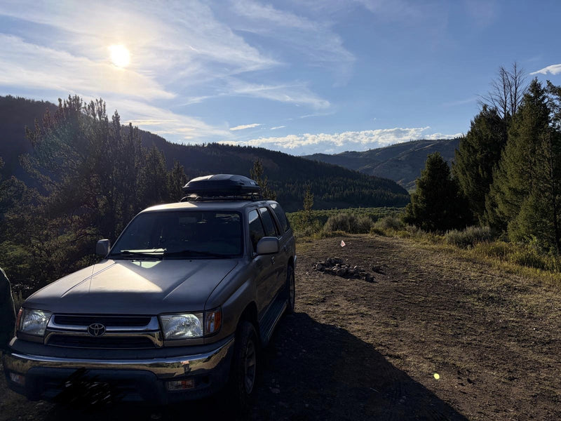 4Runner parked at a backcountry campsite with a fire ring, forested ridgelines behind it — photo 5