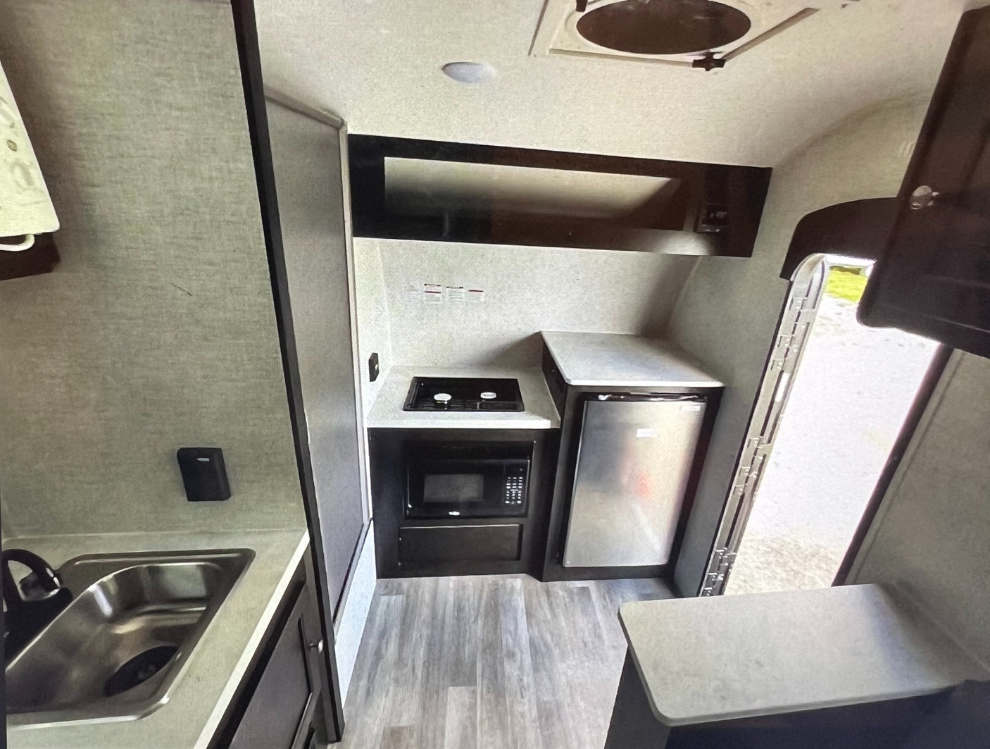 Functional RV rental kitchen: sink, two-burner stove, microwave, and refrigerator. Essential amenities for travel.