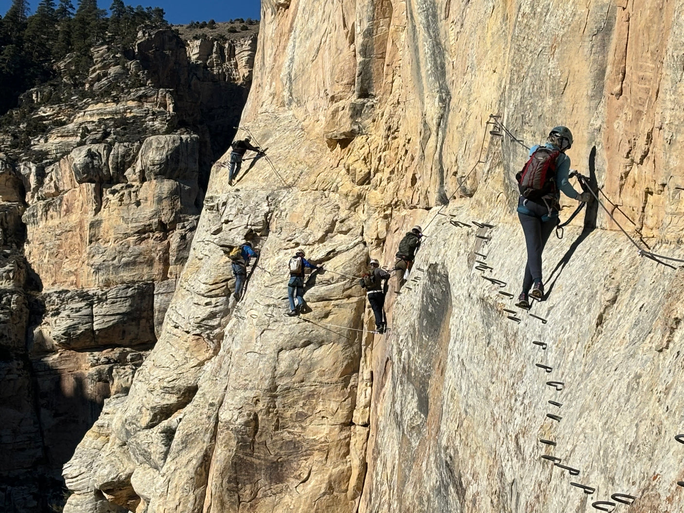 Experience cliffside adventure after your RV rental! Climbers navigate a via ferrata on a stunning mountain face.