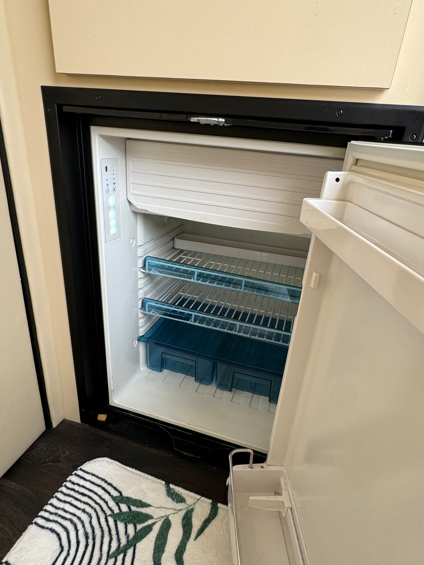 Compact refrigerator open in an RV rental. Features interior shelves, a freezer section, and control panel.