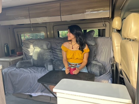 Relaxing inside a cozy RV rental. This van interior shows a woman with a mug, perfect for mobile living adventures!