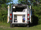 Back of a grey **rv rental** conversion van open, revealing a bed & gear storage, perfect for travel adventures.