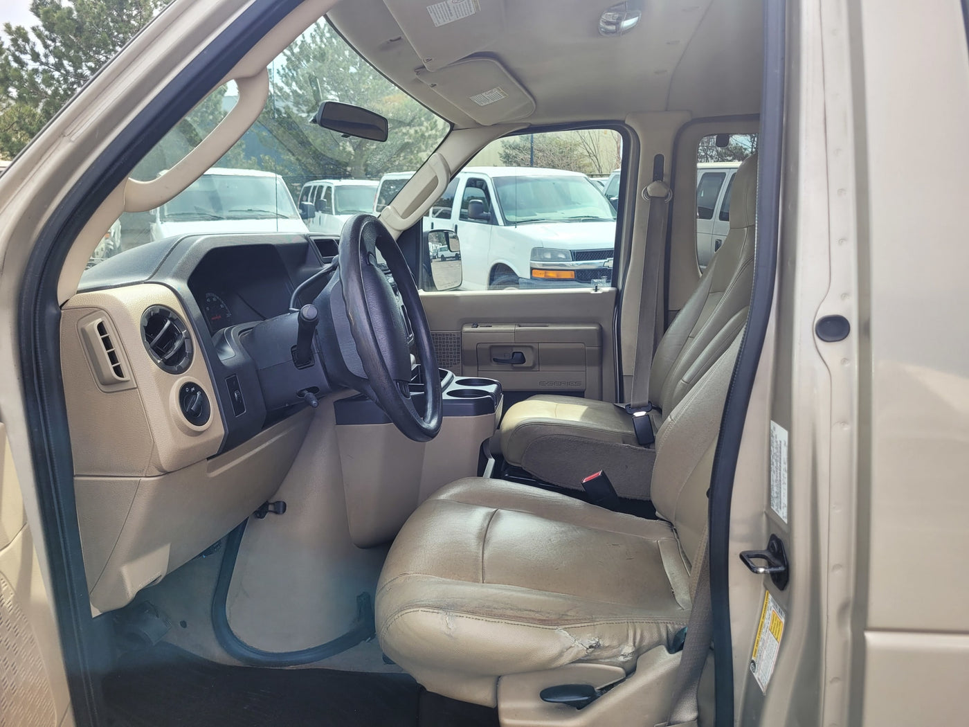 Interior of an E-Series commercial van, suitable for rv rental. Driver's cabin, dashboard, worn beige seats. — photo 4