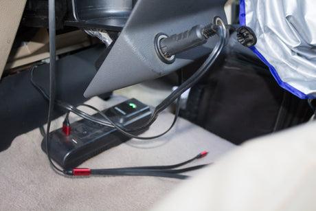 RV rental interior showing a car charger, power strip with green light, and USB cables on the floor for travel charging.