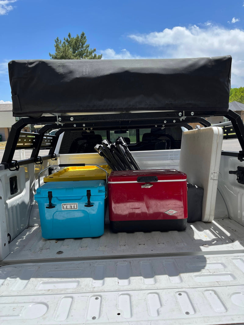 An rv rental truck bed filled with camping gear: red & blue coolers, a table, and chairs under a rack. — photo 4