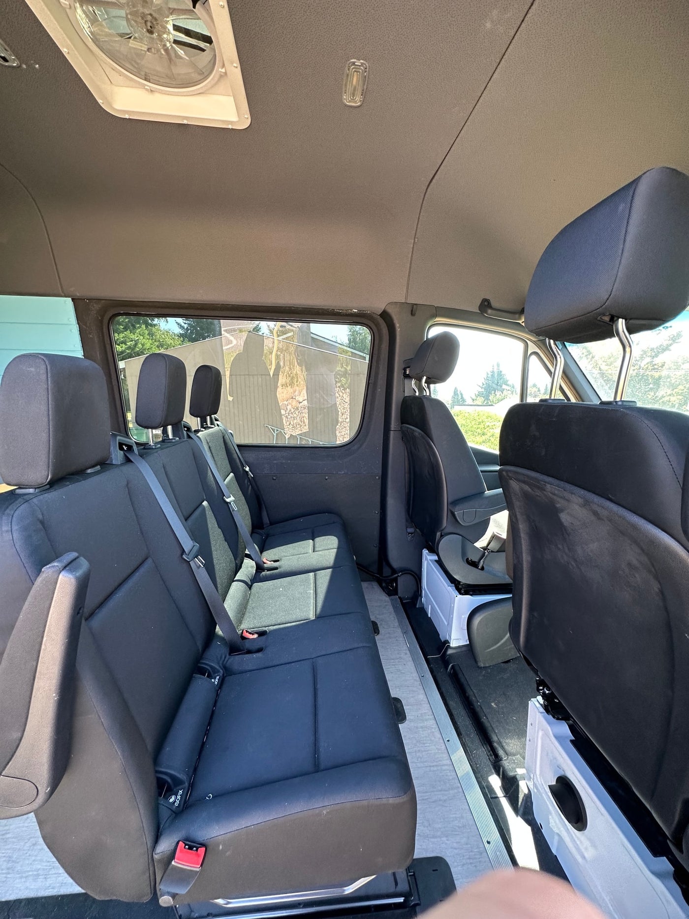 Inside a spacious RV rental: multi-row black seating, light flooring, and a ceiling fan. — photo 7