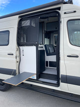 White camper van RV rental, side door open showing interior, mesh screen, and pull-out table for outdoor living.