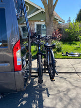 RV rental with bikes ready for adventure! A grey van with two bikes on a rear rack, parked in a sunny driveway.