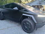 Matte black Tesla Cybertruck, an angular EV, parked on a driveway. Not an RV rental, but a bold choice for adventures.
