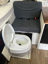 This RV rental features a hidden pull-out portable toilet, a convertible bench seat/bed, and a compact kitchen area.