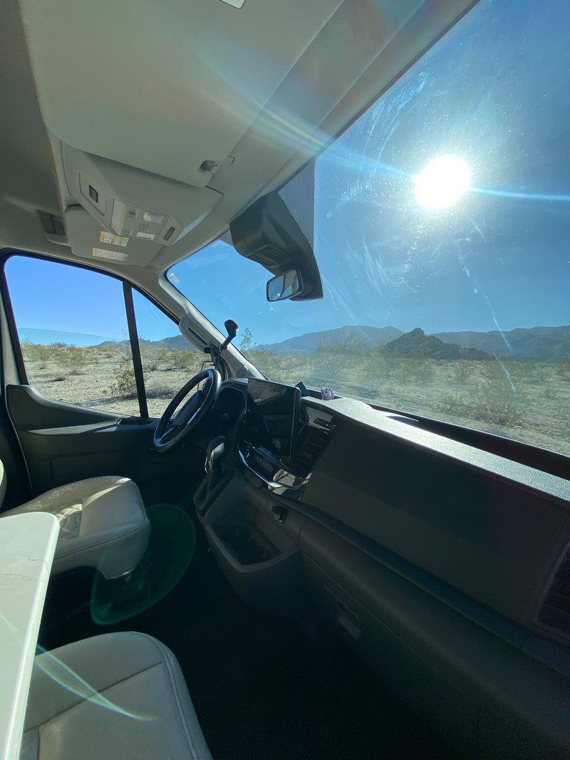 Inside a bright RV rental camper van. Sun glares on the windshield, revealing desert views and distant mountains. — photo 8