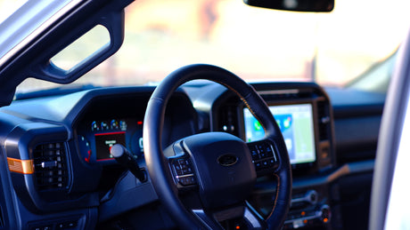 Spacious, modern RV rental interior: view of the dashboard, steering wheel with controls, and large navigation screen.