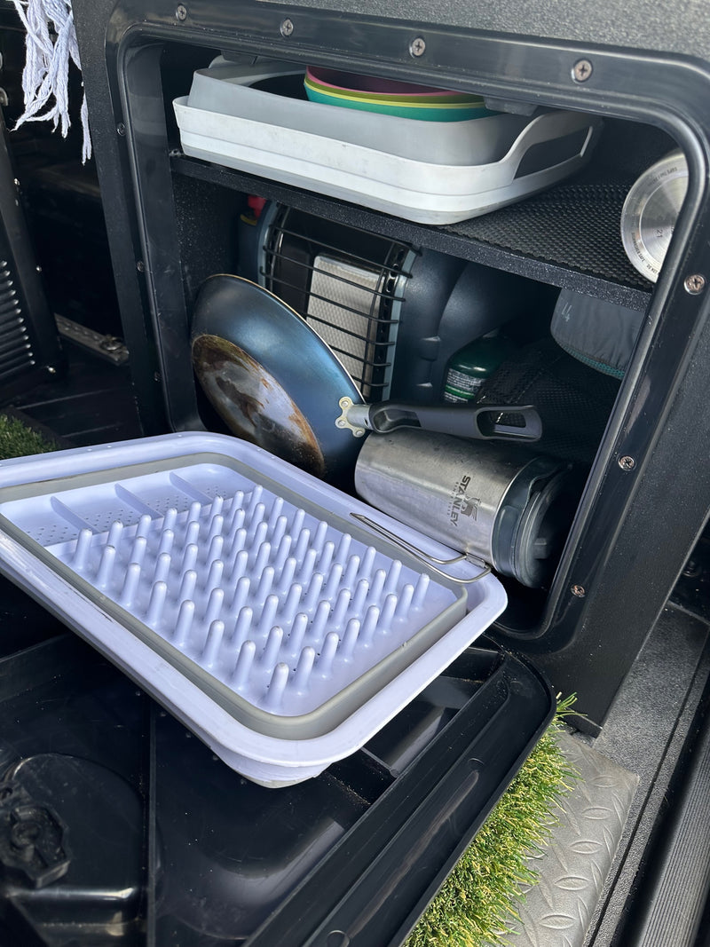 RV rental setup: Organized compartment with camp stove, frying pan, Stanley mug, and dish drying rack. Essential camping gear. — photo 19