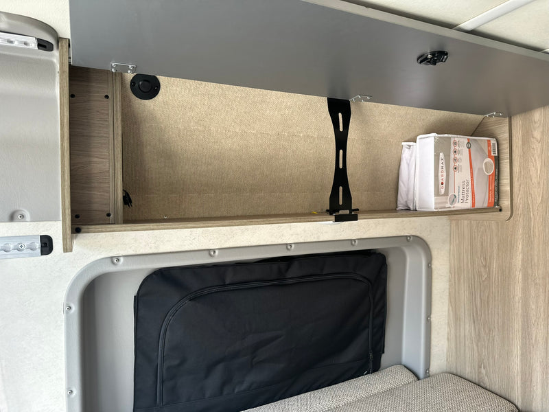 RV rental overhead storage. Open cabinet reveals a mattress protector, ideal for compact travel. — photo 3
