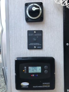 Manage your RV rental power: battery disconnect, generator controls, & solar charge controller displaying 12.4V. — photo 14