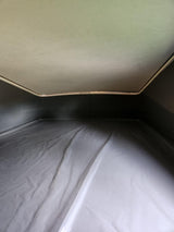 Inside an RV rental's pop-top bed: A cozy sleeping area with a light ceiling, dark sides, and a covered mattress below.