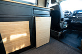Inside an rv rental, a custom camper van kitchenette with bamboo details, fridge, and Mercedes Sprinter cockpit.