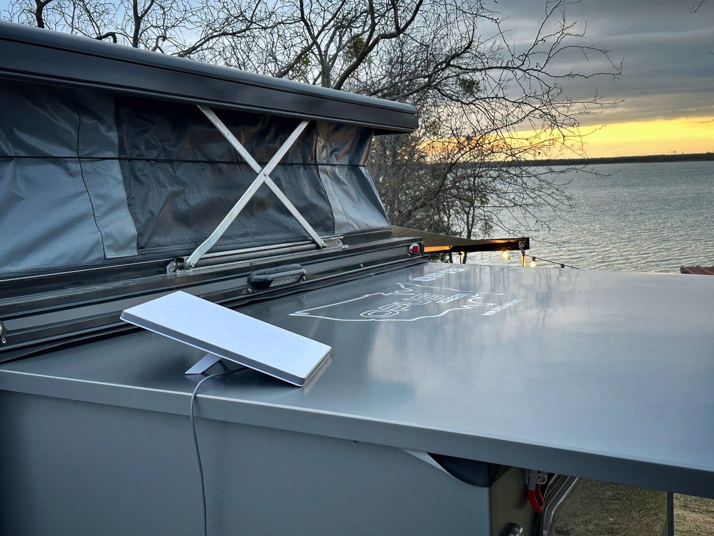 RV rental with a pop-up tent and Starlink dish, providing internet by a lake at sunset.