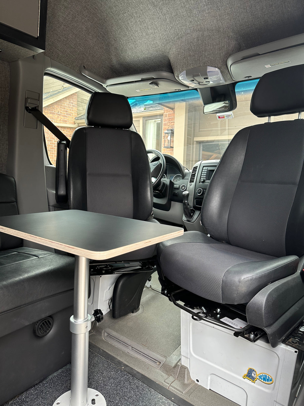 Inside a modern RV rental camper van: swiveling front seats, a sturdy table, and a bench seat for a versatile living space. — photo 3