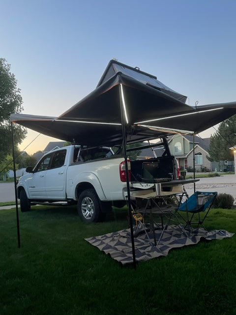 Spacious outdoor setup: White truck with a lighted 270-degree awning, rug, and chairs, ready for your next rv rental camping adventure. — photo 3