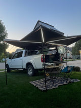 Spacious outdoor setup: White truck with a lighted 270-degree awning, rug, and chairs, ready for your next rv rental camping adventure.