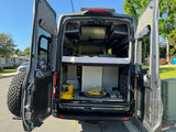 Open rear doors of an RV rental campervan reveal a cozy bed, smart storage solutions, and essential camping gear for your travels.