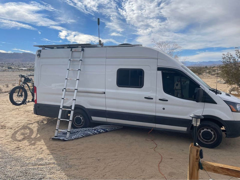  parked on a sunny street. Ideal for travel & adventure.|Off-grid RV rental adventure: White Ford Transit van with bike — photo 3