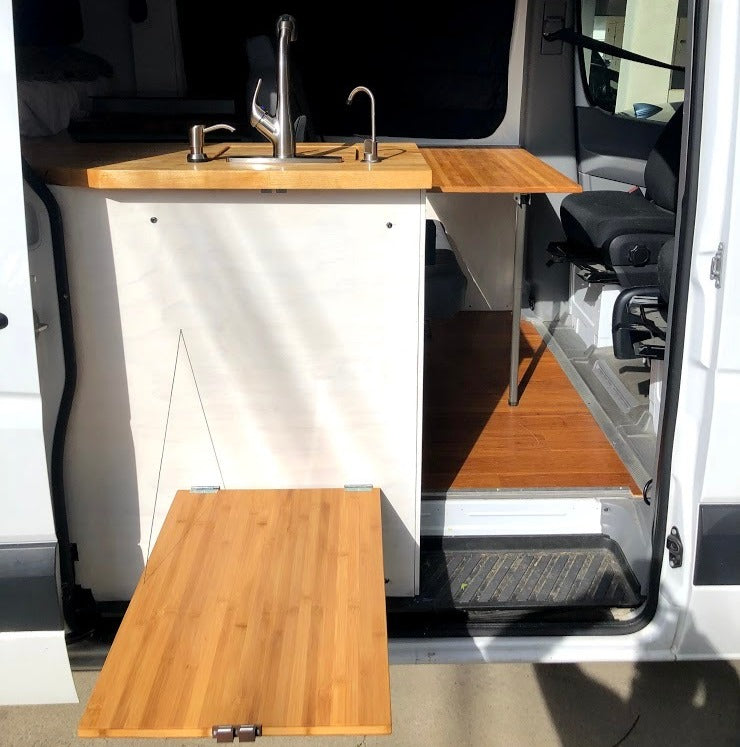 RV rental: Camper van kitchen showing sink, faucet, & two versatile folding bamboo tables.