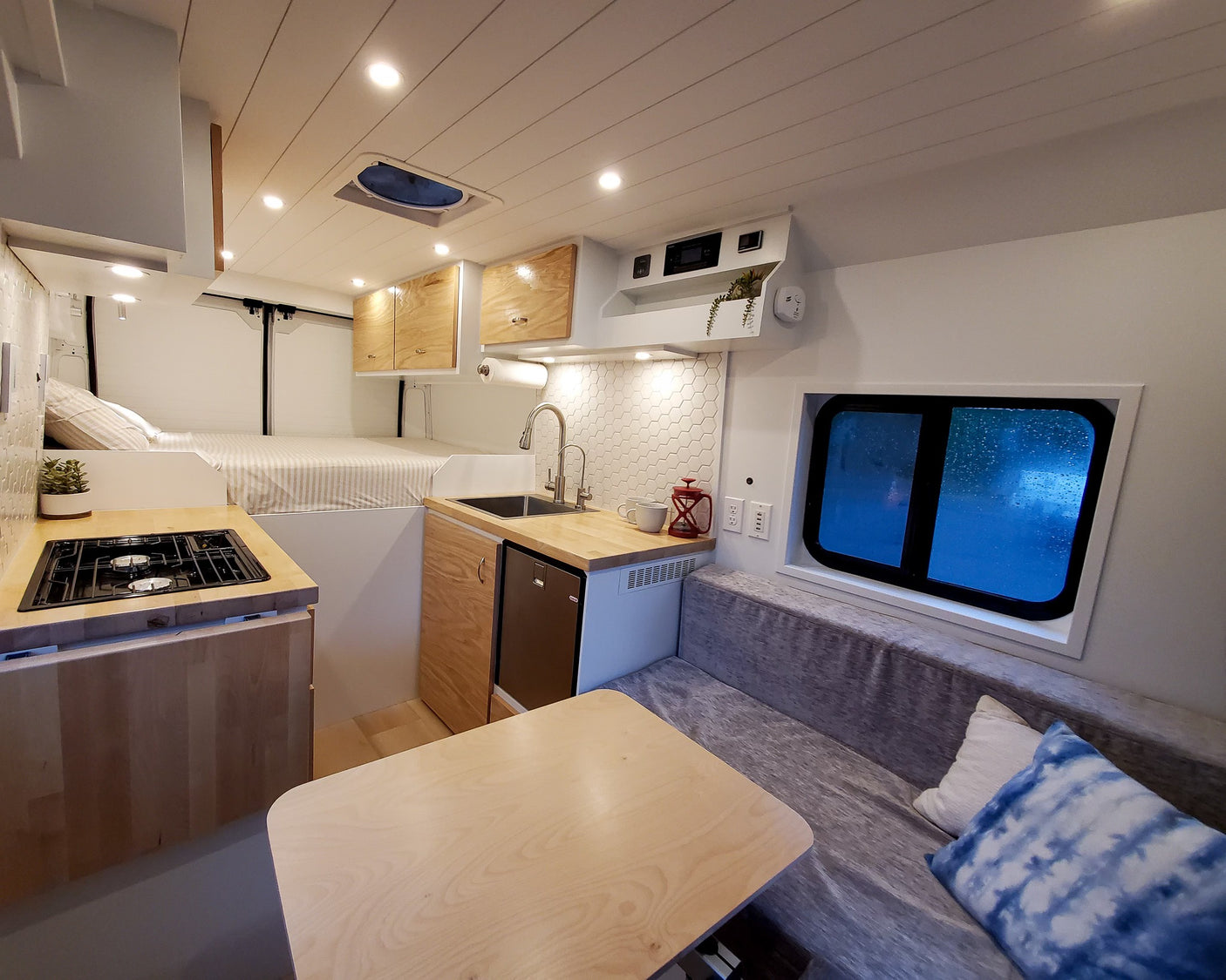 A cozy, modern RV rental interior featuring a kitchen, comfortable bed, and dining area, ready for your next adventure.