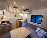 A cozy, modern RV rental interior featuring a kitchen, comfortable bed, and dining area, ready for your next adventure.