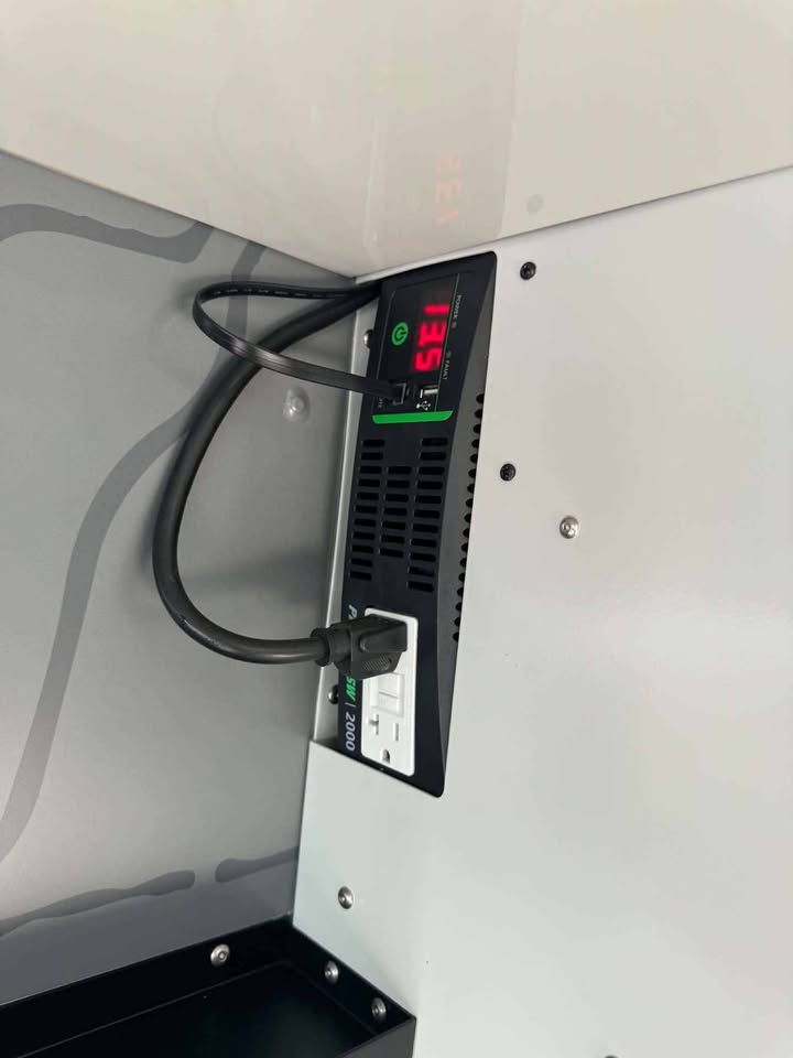 2,000W pure sine wave inverter mounted inside the galley of the XPedition Voyager Sky XE with its digital readout lit and AC outlet in use — photo 13
