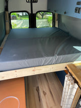 Explore this RV rental's comfy bed, overhead storage, & hardwood floors in a spacious camper van interior.