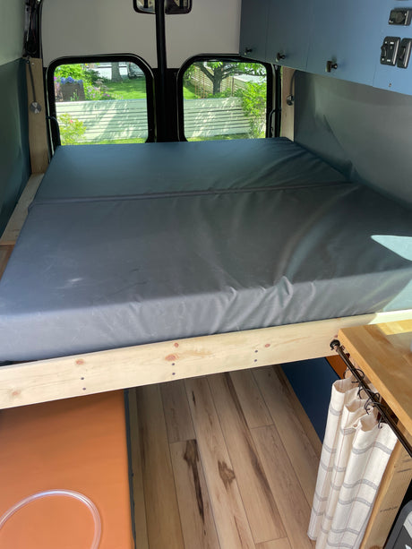 Explore this RV rental's comfy bed, overhead storage, & hardwood floors in a spacious camper van interior.