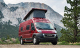 Red pop-top camper van for RV rental outdoor adventures, set against a stunning mountain backdrop.