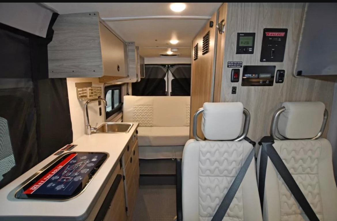  and dining areas.|A white Winnebago Solis camper van with an extended pop-top roof — photo 7