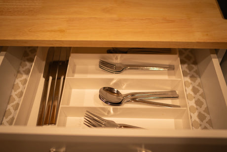RV rental kitchen drawer open, revealing organized knives, forks, and spoons in a white cutlery tray.