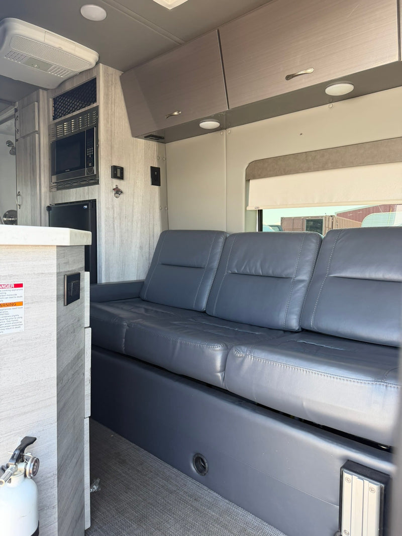  possibly a compact bathroom.|RV rental interior: View of front vehicle seats and a grey leather-look sofa on the left — photo 5