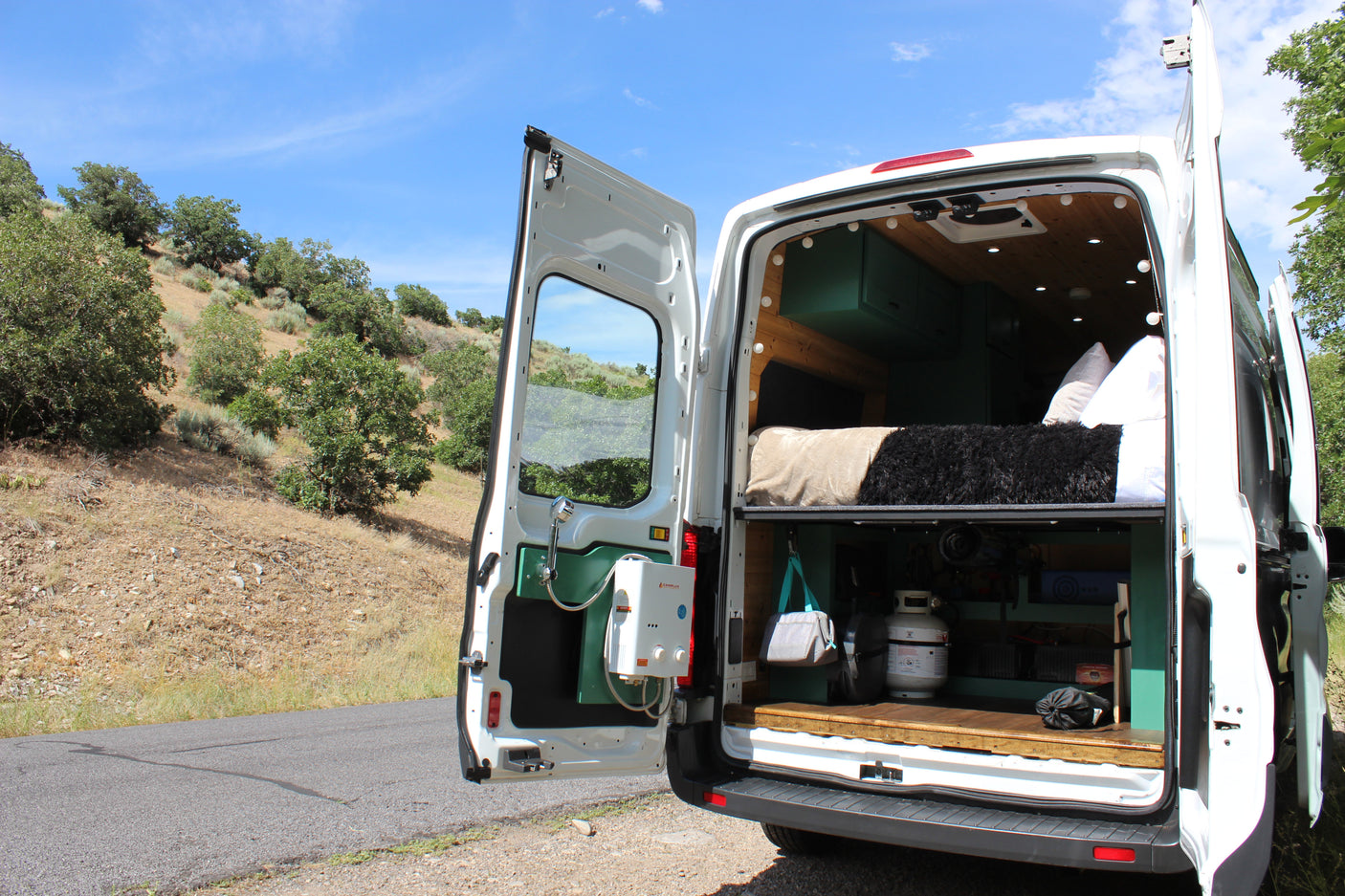 Explore the wilderness in our rv rental camper van, featuring a custom interior, cozy bed, and outdoor shower.