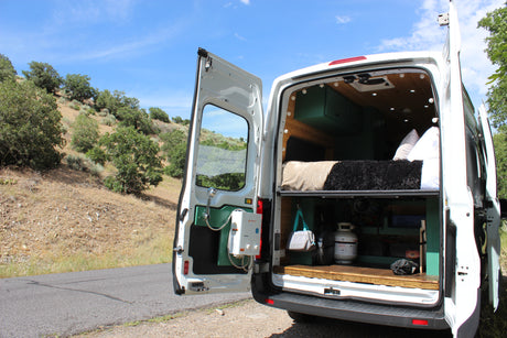 Explore the wilderness in our rv rental camper van, featuring a custom interior, cozy bed, and outdoor shower.