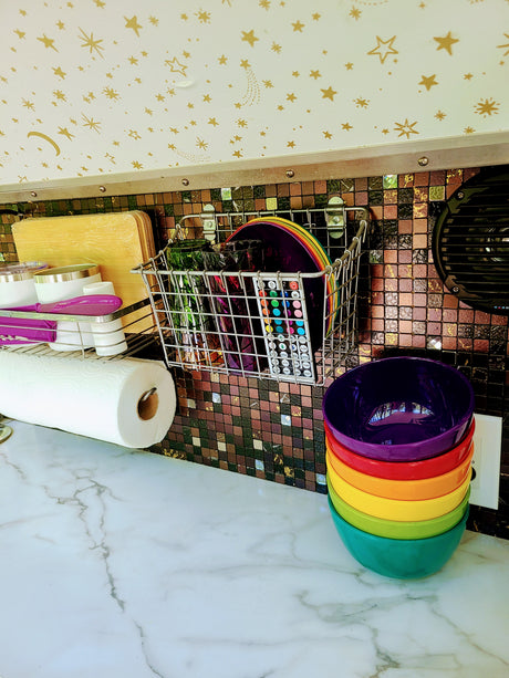 Organized RV rental kitchen featuring a starry ceiling, mosaic tile backsplash, colorful bowls, and smart storage solutions.