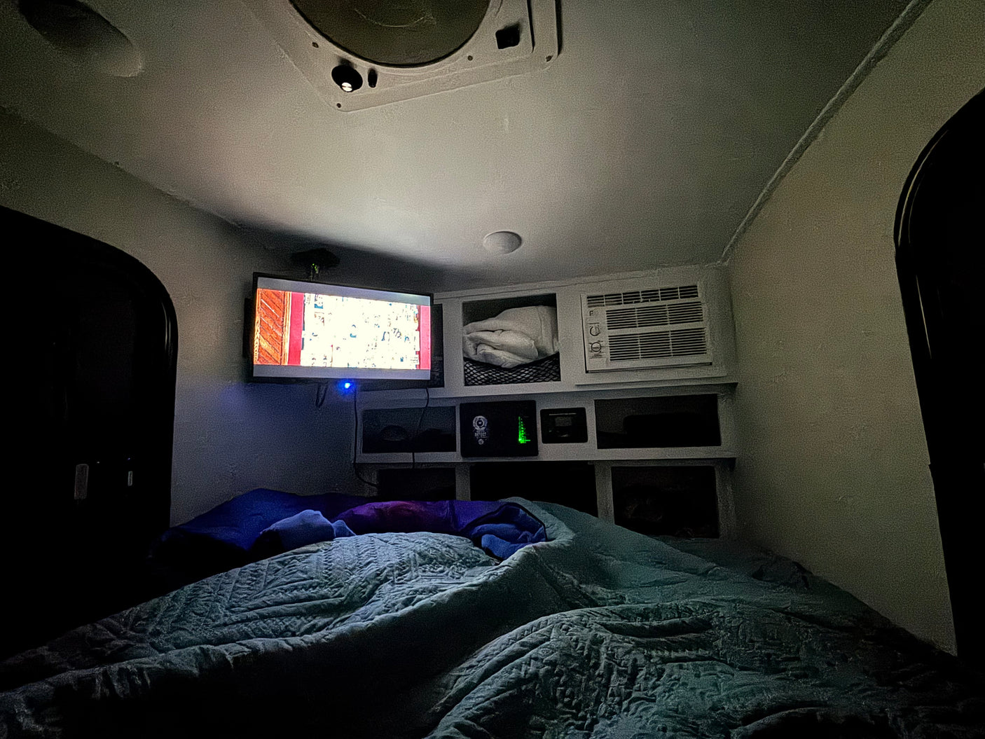 Cozy RV rental interior with a comfy bed, TV for entertainment, and compact storage, perfect for a night in.