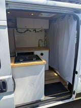 Step into this rv rental camper van: a bright interior featuring a compact kitchen with stove, sink, and charming decor.