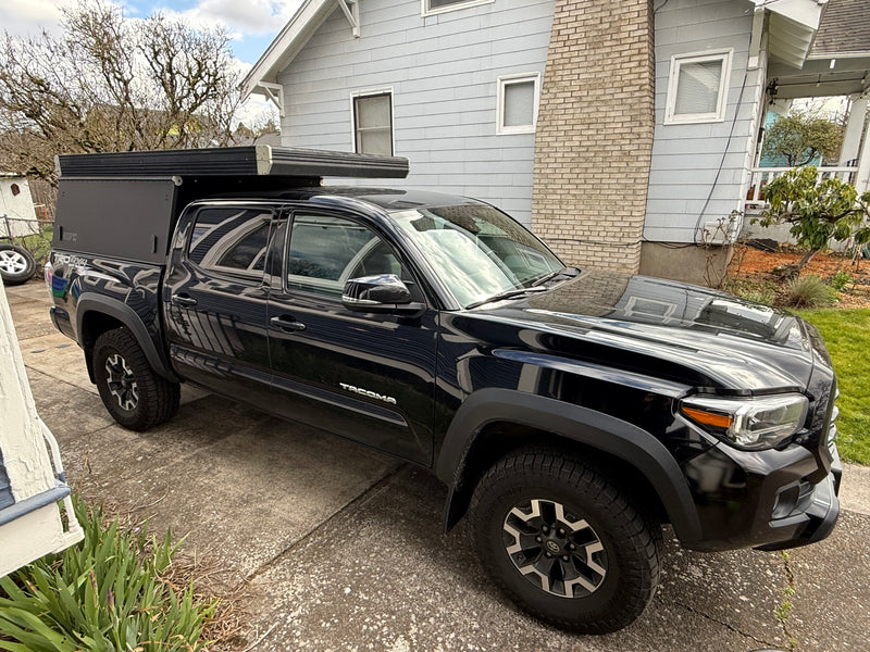 Black Toyota Tacoma truck with a pop-top camper, ideal for an rv rental or off-road adventure. — photo 4