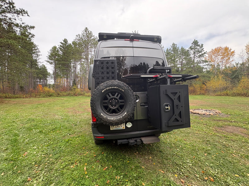  is parked in a grassy forest clearing.|Gray off-road camper van — photo 11